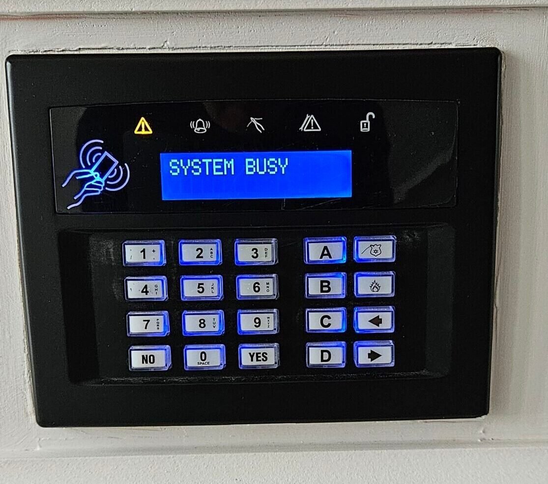 A black security alarm keypad with a blue screen | Home Security Installation